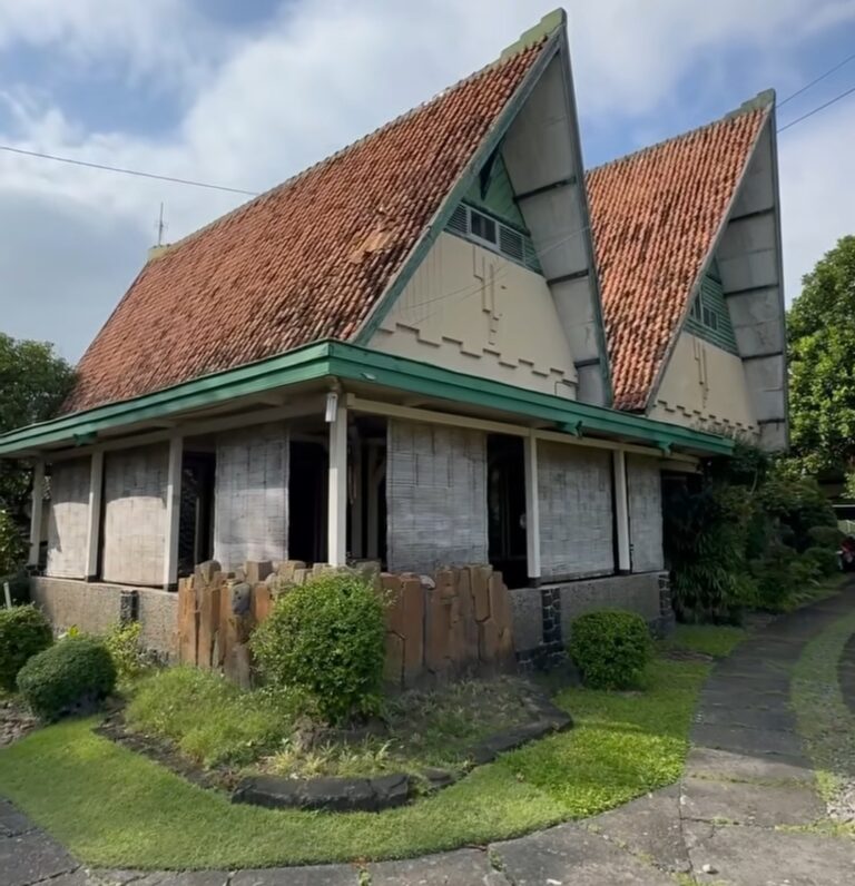 Screenshot_20260520_195128_Instagram - Mabur.co Two pointed-roof house with red clay tiles, green trim, and a small garden in front