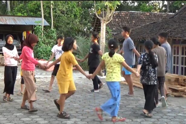 Group of children and teenagers forming a circle by holding hands and playing a game in a village yard.