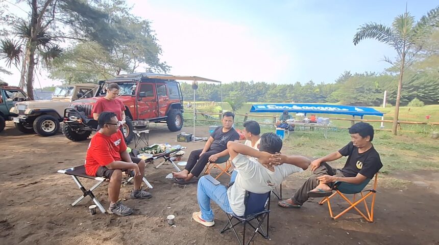Screenshot_20260612_162104_Gallery - Mabur.co Group of men sitting in folding chairs around a small table with snacks, outdoors near parked off-road vehicles under trees.