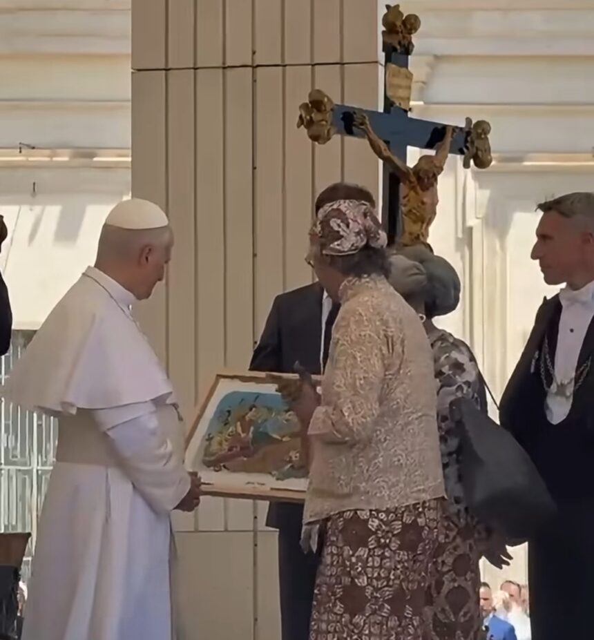 A pope-like figure in white robes receives a framed painting from a woman in a lace dress at a ceremonial gathering, with a crucifix in the background.
