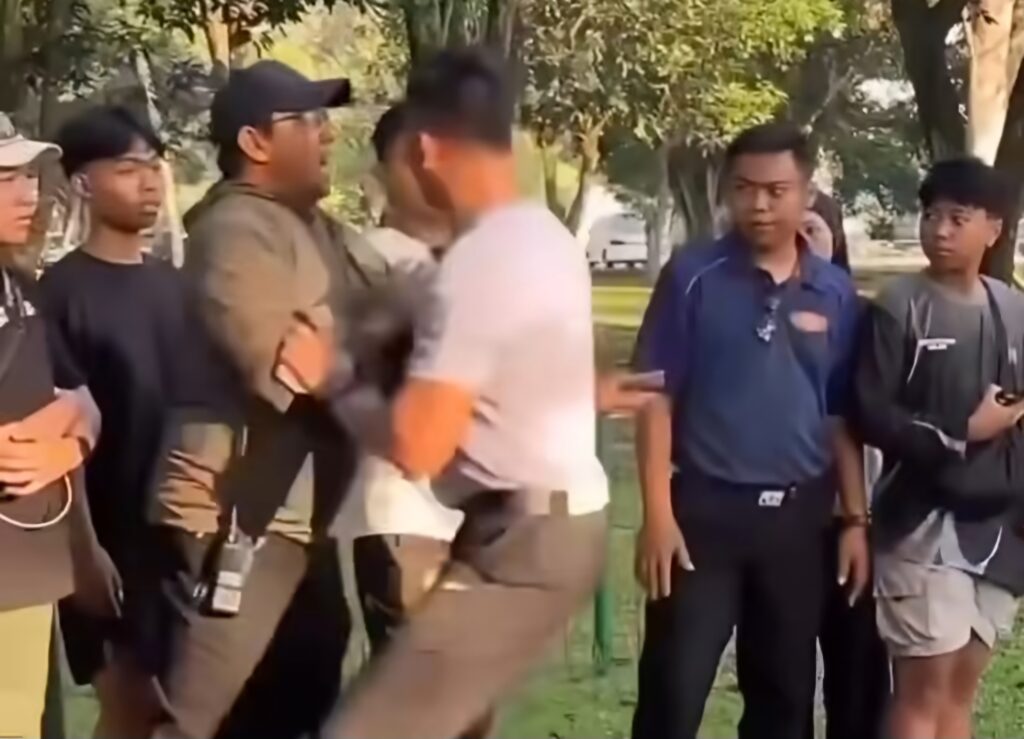 Screenshot_20260621_223528_Instagram - Mabur.co Group of young men standing together in a park, talking or listening amid trees on a sunny day.