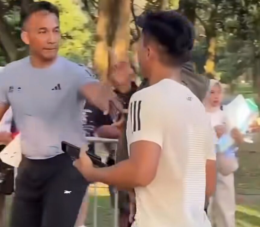 Sosok Brigjen Yuniar Dwi Hantono, Komandan Korem (Danrem) 072/Pamungkas saat terlibat insiden dalam Mandiri Jogja Marathon 2026 (foto : Instagram) - Mabur.co Two men talking in a park: one facing the camera in a gray T-shirt, the other with his back to the camera; trees in the background.