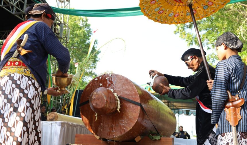 Screenshot_20260711_180007_Gallery - Mabur.co Group of people in traditional clothing performing a ceremonial drum beat on a large wooden drum.