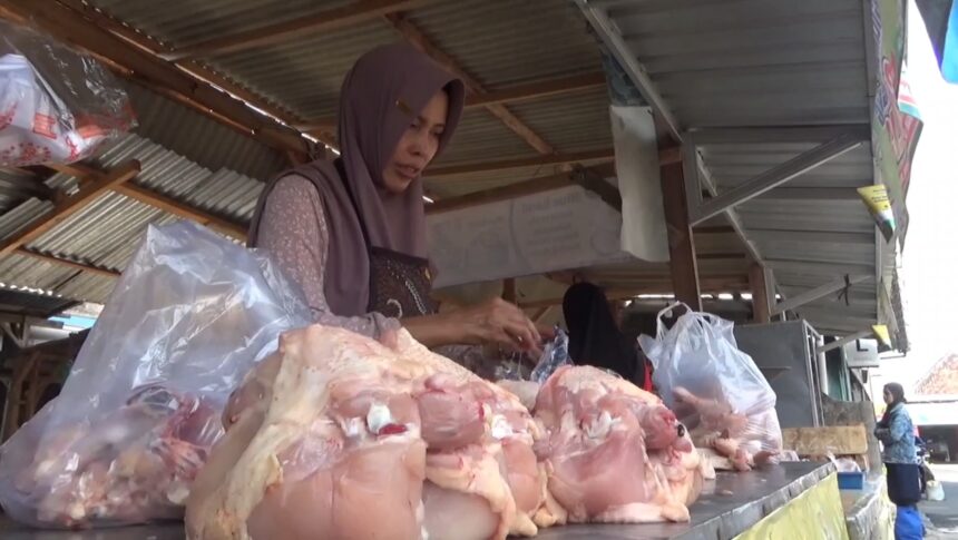 Woman wearing a hijab at an outdoor meat stall, handling large cuts of raw meat on a counter