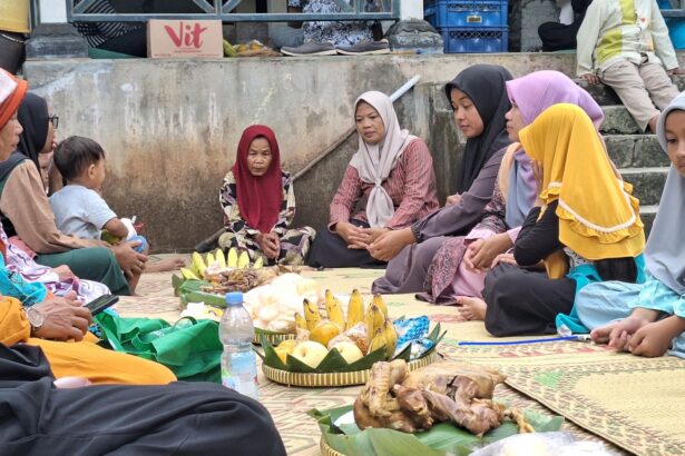 A group of women and a child sit cross‑legged on a mat in a circle, sharing food and drinks outdoors.