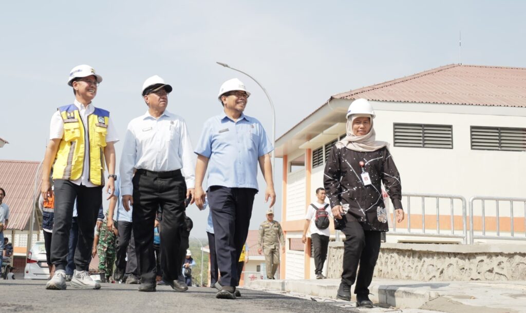 Group of professionals in hard hats walking outdoors on a sunny day beside a building