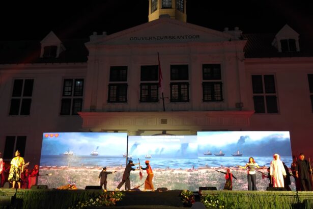 Nighttime stage performance in front of a white government building with 'GOUVERNEURSKANTOOR' on the facade and LED screens showing a seaside scene with ships.