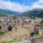 Town on a hillside being hit by a massive landslide sending dust and debris through buildings below
