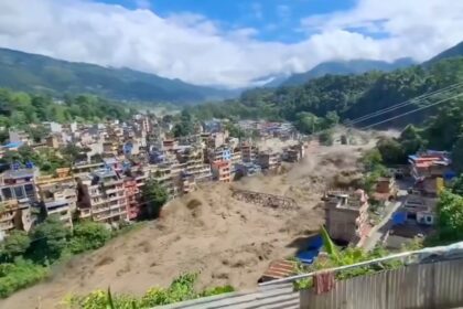 Town on a hillside being hit by a massive landslide sending dust and debris through buildings below