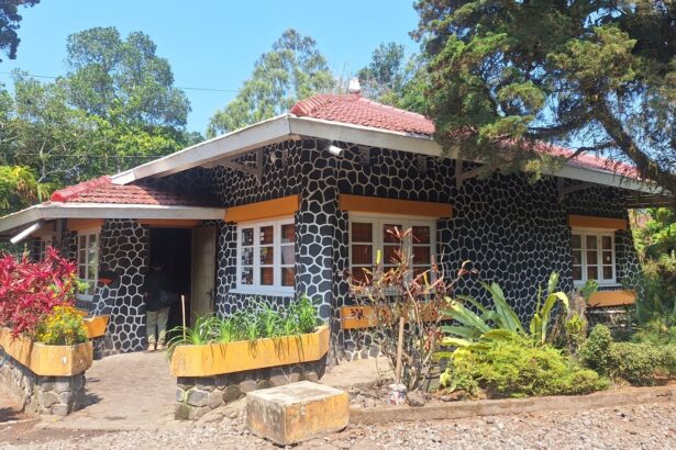 Stone-pattern cottage with a red tile roof, orange window awnings, and a lush garden in front.