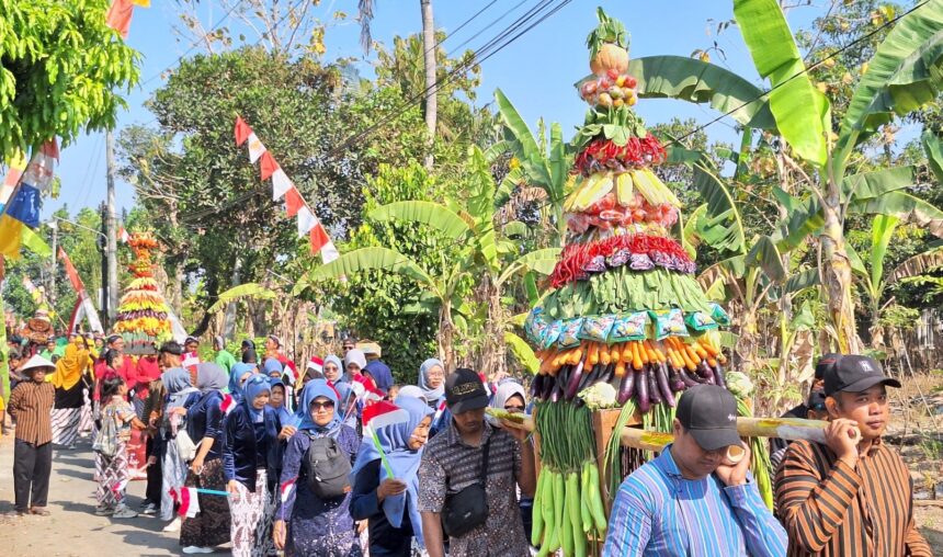 Colorful fruit-and-vegetable sculpture carried in a street festival, with onlookers in traditional clothing nearby.