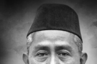 Black-and-white head-and-shoulders portrait of a middle-aged man wearing a suit, striped tie, and a traditional cap.