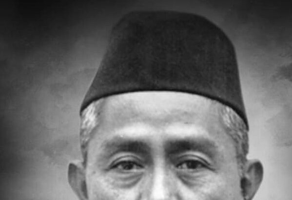 Black-and-white head-and-shoulders portrait of a middle-aged man wearing a suit, striped tie, and a traditional cap.