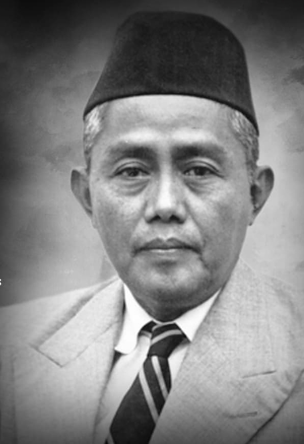 Black-and-white head-and-shoulders portrait of a middle-aged man wearing a suit, striped tie, and a traditional cap.