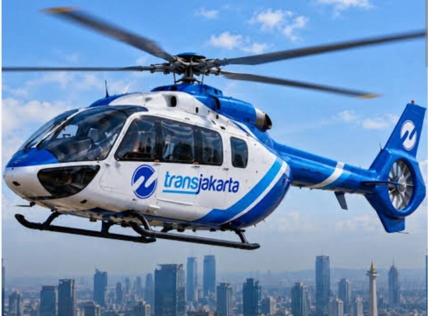 Blue and white Transjakarta helicopter in flight over a city skyline.
