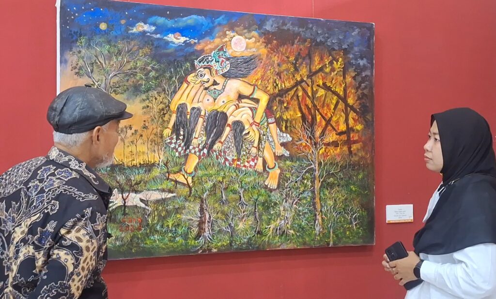 Screenshot_20261013_115305_Gallery - Mabur.co Two visitors, an elderly man and a woman in a hijab, view a vibrant painting on a red gallery wall.