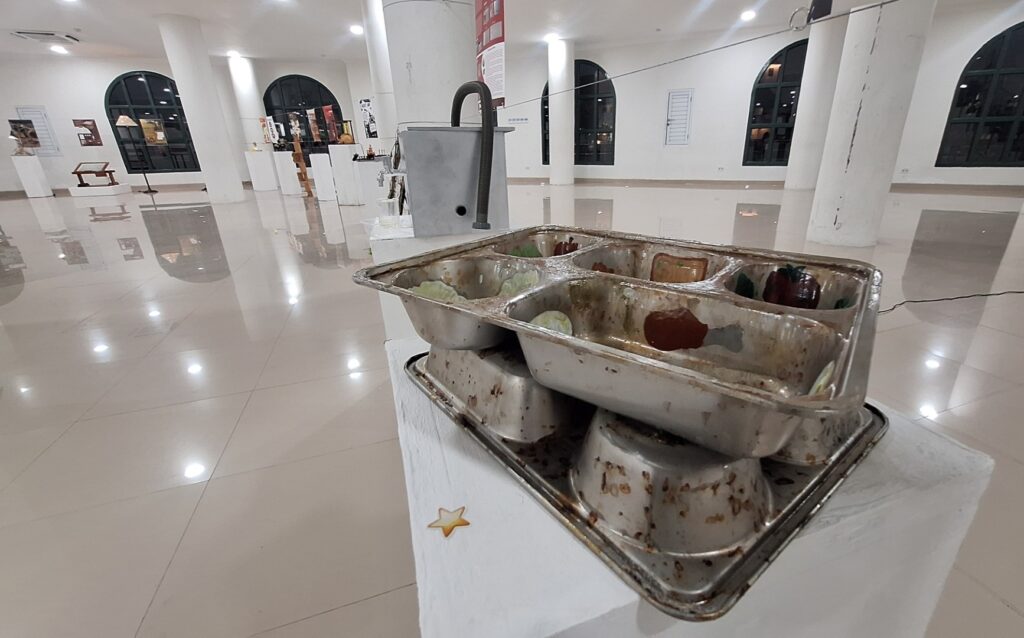 Screenshot_20261014_012558_Gallery - Mabur.co Rusty metal serving trays stacked on a white pedestal in a bright, modern gallery with white floors and arched windows in the background.