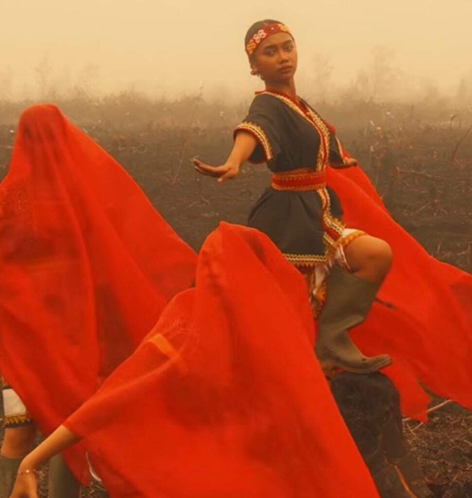 Screenshot_20261022_222923_Instagram - Mabur.co Young woman in traditional dress dancing among flowing red fabrics in a foggy field.