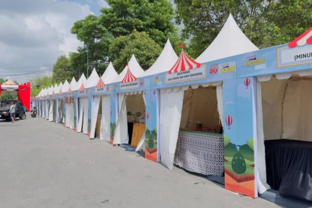 Row of blue festival stalls with white tents and red striped tops lined along a street for an outdoor fair or carnival.