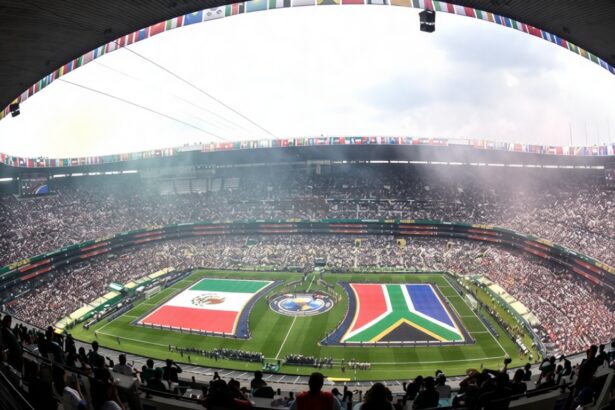Bird's-eye view of a full stadium with a circular field display featuring large national flags and cheering spectators.