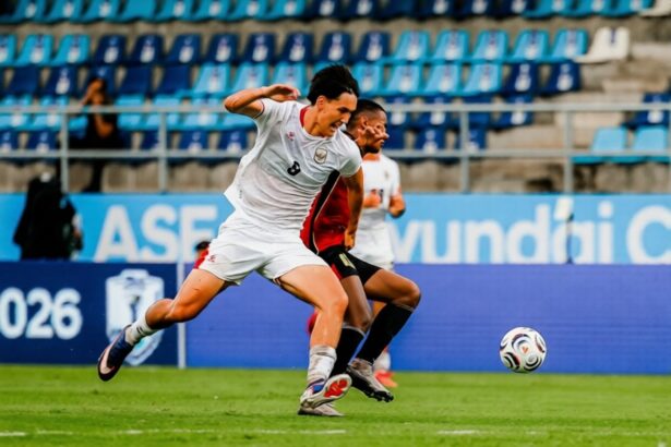 Soccer players chase a ball on a green field; a white jerseyed player (number 8) leads with a sprint while an opponent in red pursues