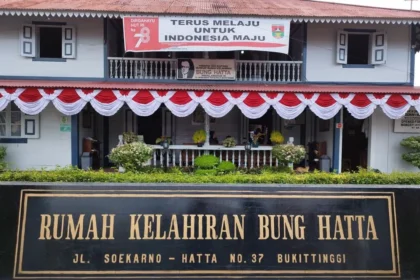 Front facade of Bung Hatta Birth House with red-white bunting and a large black-and-gold sign reading 'RUMAH KELAHIRAN BUNG HATTA' at No. 37, Bukittinggi