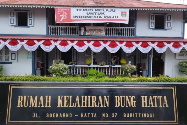 Front facade of Bung Hatta Birth House with red-white bunting and a large black-and-gold sign reading 'RUMAH KELAHIRAN BUNG HATTA' at No. 37, Bukittinggi