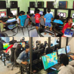 Children sit at computer desks in a bright gaming center, each focused on their monitor while playing games with headphones on.