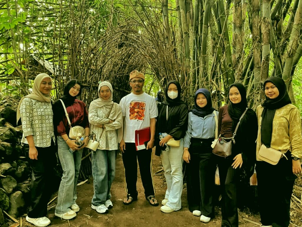 Group of nine people posing together in a bamboo tunnel, outdoors, smiling at the camera.