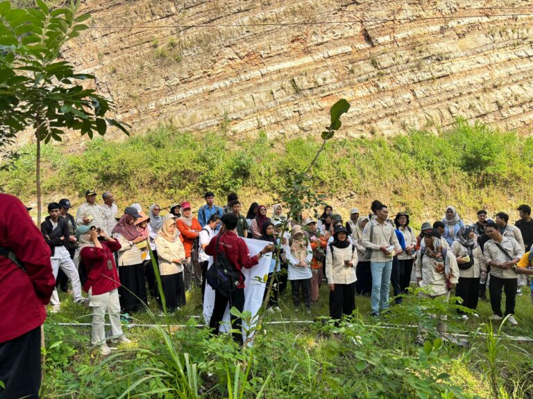 WhatsApp Image 2026-05-20 at 2045061 - Mabur.co Group of students and adults gathered for an outdoor event, standing in a grassy area in front of a layered rock cliff.