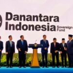 Group of officials in suits on a blue stage with a podium, in front of a Danantara Indonesia Sovereign Fund backdrop logo.