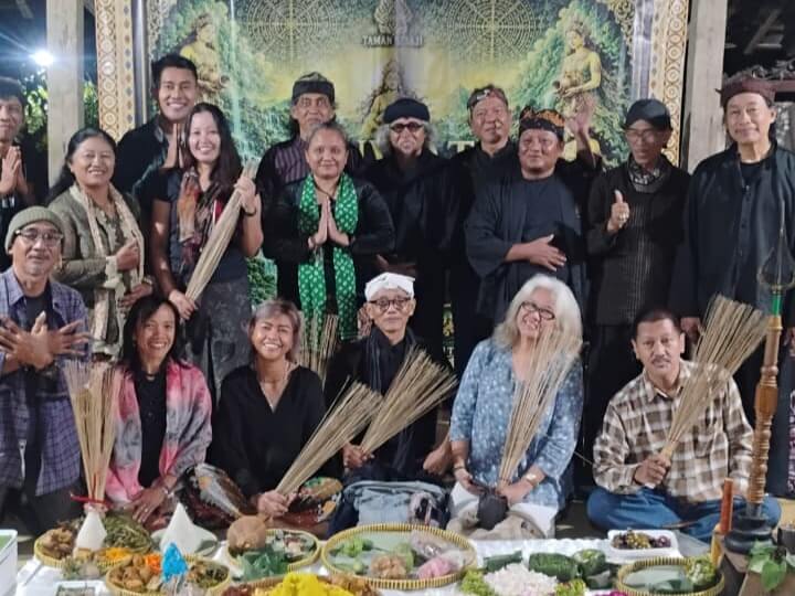 WhatsApp Image 2026-07-05 at 070747 - Mabur.co Group of adults posing for a group photo at a cultural ceremony, several holding palm fronds, with ritual food offerings arranged in front.