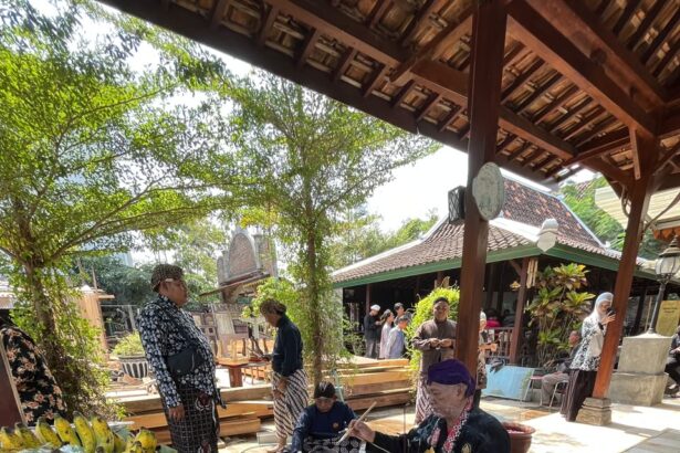 Market scene with banana leaf platters of food, eggs, bananas, and vegetables as people in traditional clothing browse under a wooden pavilion.