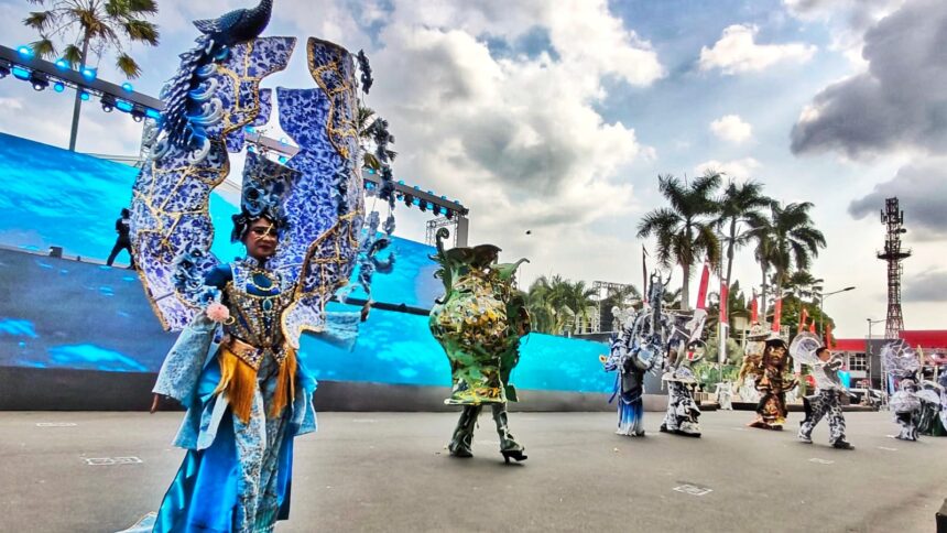 Performers in elaborate blue dragon costumes perform on a large outdoor stage with palm trees in the background.