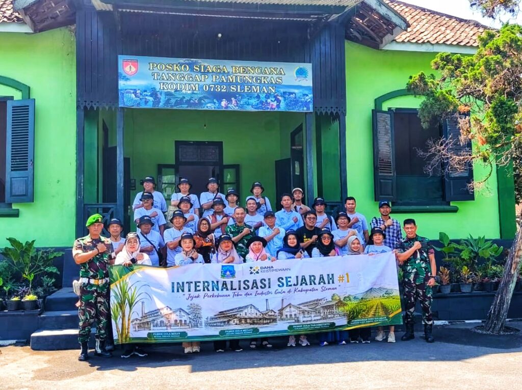 WhatsApp Image 2026-08-15 at 191609 - Mabur.co Group of people posing with a banner reading 'Internalisasi Sejarah #1' in front of a green building with military personnel on sides.