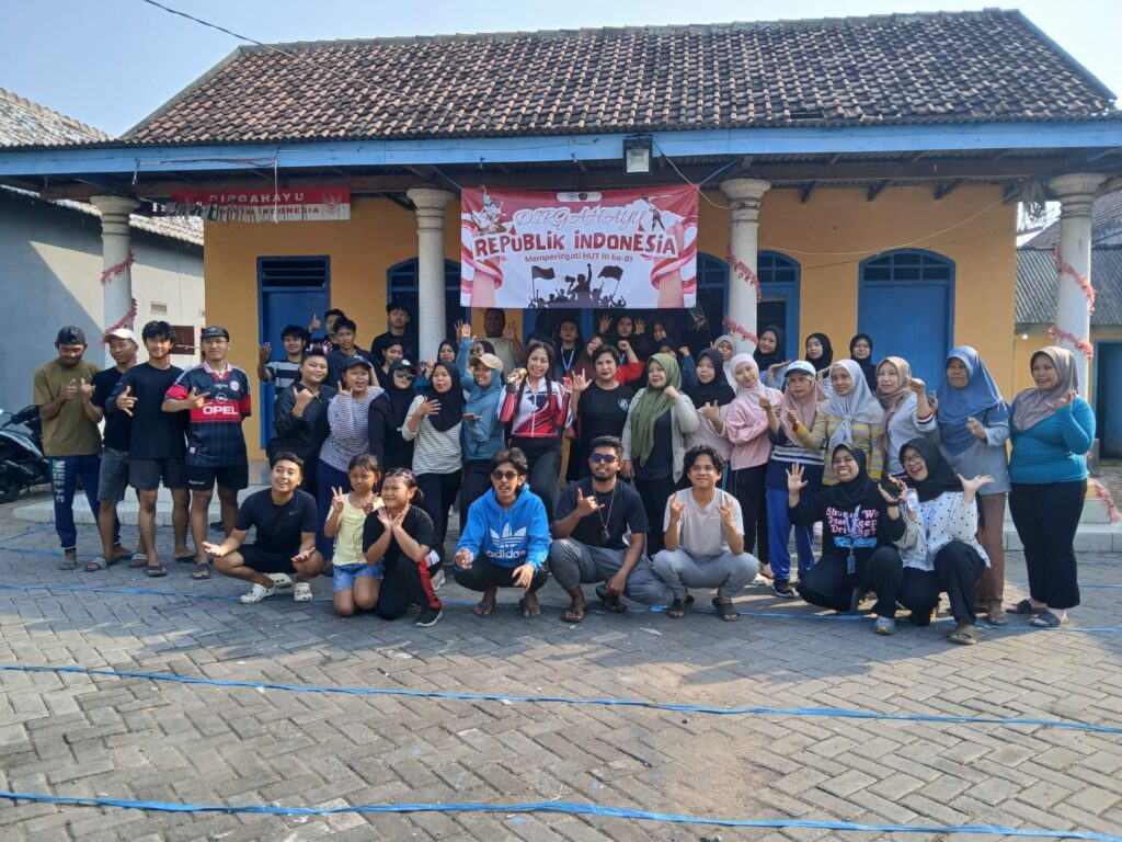 WhatsApp Image 2026-08-18 at 120359 - Mabur.co A large group of men, women, and children pose together outside a yellow building with a banner that reads 'Republik Indonesia' in the center.