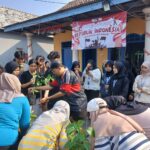 Crowd of people, many in hijabs, planting young saplings together at an outdoor Indonesia Independence Day event with a banner in the background.