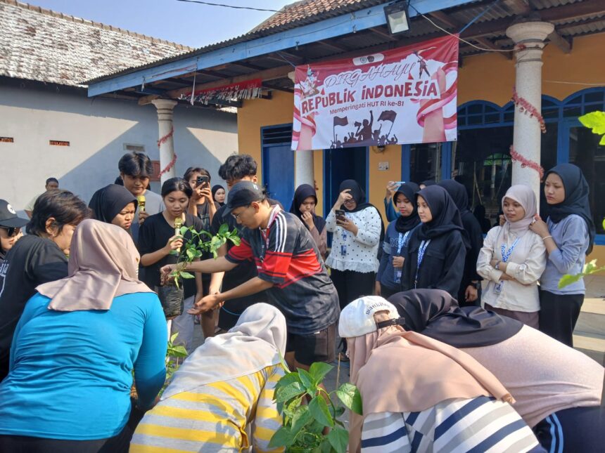 Crowd of people, many in hijabs, planting young saplings together at an outdoor Indonesia Independence Day event with a banner in the background.