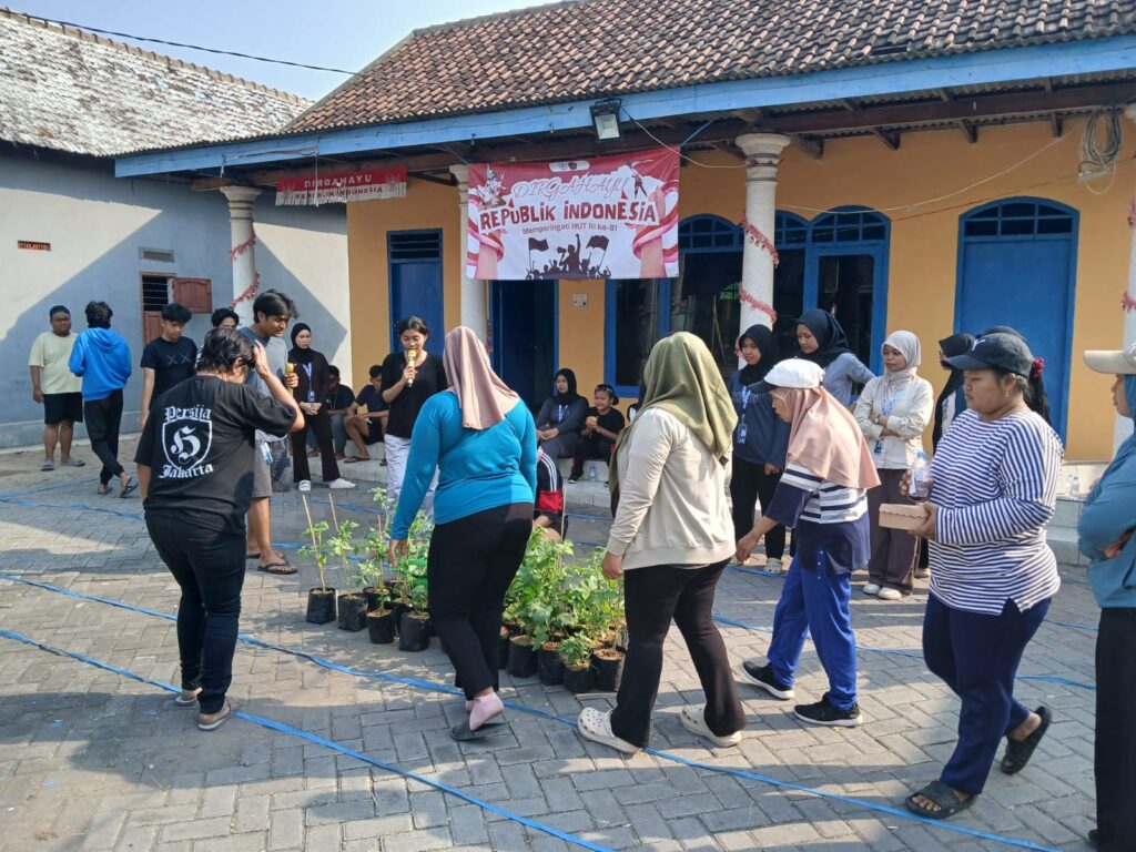 WhatsApp Image 2026-08-18 at 1204001 - Mabur.co Community gathering in a courtyard for Indonesia Independence Day, with a speaker holding a microphone beside potted plants.