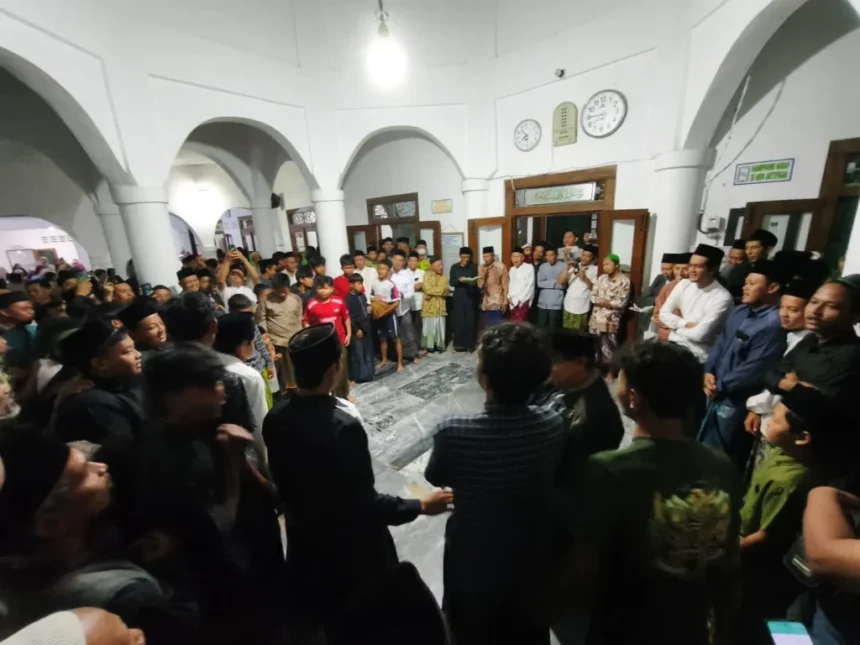 Large crowd of men and boys forming a circle in a white arched hall during a community gathering, center of attention unclear