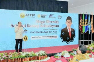 Speaker at a podium on a stage with a blue banner reading 'Mega Diversity' during a cultural event at Universitas Tunas Pembangunan Surakarta (UTP Surakarta).