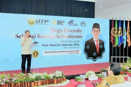 Speaker at a podium on a stage with a blue banner reading 'Mega Diversity' during a cultural event at Universitas Tunas Pembangunan Surakarta (UTP Surakarta).