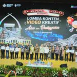 Group photo on stage after a creative video content competition, holding certificates with a large event banner behind them reading ‘Lomba Konten Video Kreatif’ (Jakarta, 2026).