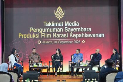 Six panelists seated on a stage during a Jakarta event with a large banner behind about a film production competition or theme.