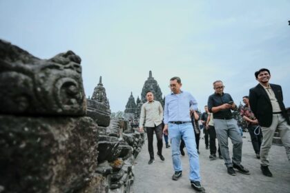 Group of men walking along ancient stone temple ruins on a wide pathway.