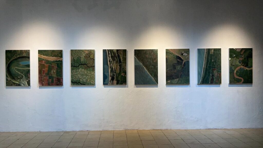 WhatsApp Image 2026-09-09 at 1055501 - Mabur.co Nine framed aerial landscape photos hang in a single row along a white gallery wall.