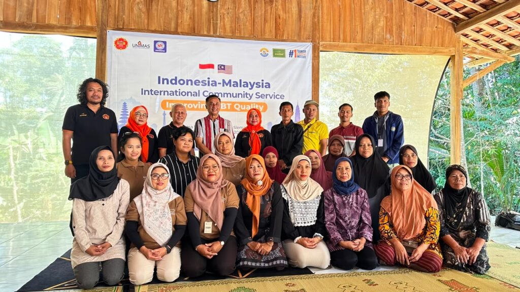 Group of men and women posing in front of an Indonesia–Malaysia banner at an outdoor event.