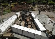 Rectangular tiled trough under construction on a stone surface, with white ceramic tiles lining the edges.