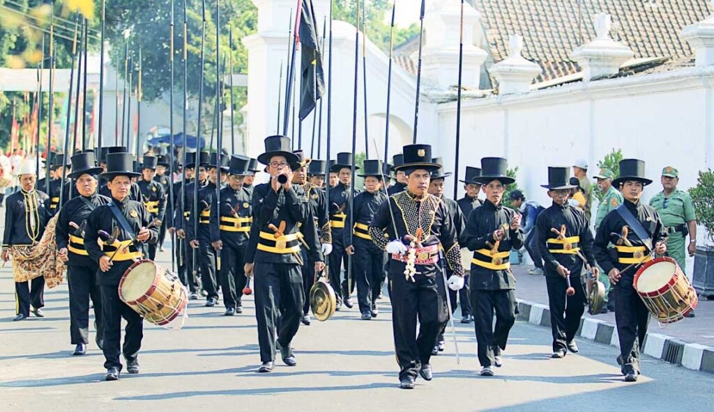 WhatsApp Image 2026-09-19 at 144854 - Mabur.co Marching band in black uniforms with top hats performing in a parade; drummers lead the group down a street.