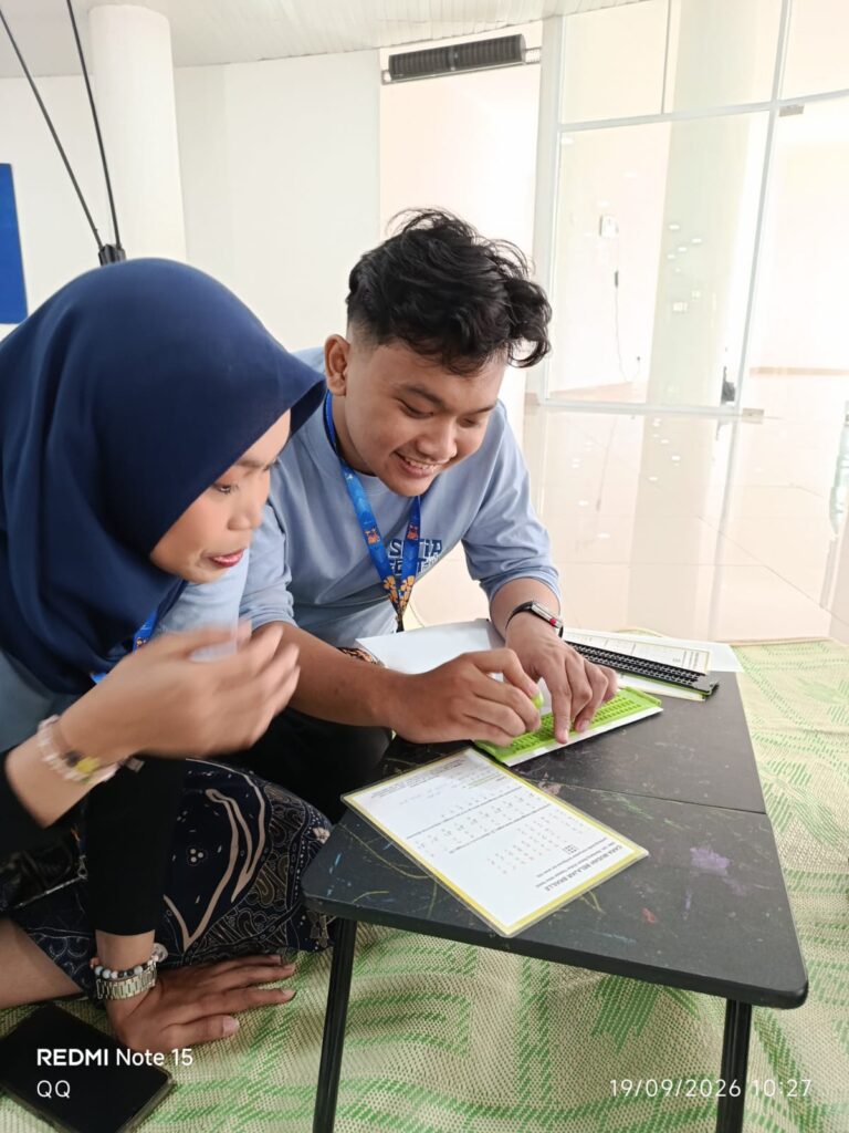 Two students collaborate at a small table, reviewing worksheets together in a bright indoor space.